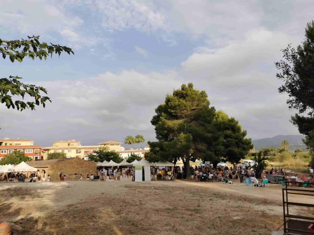 looking at the market del riurau in jesus pobre from a far distance. there are lots of umbrellas with the outside stalls, and the building of the indoor stalls